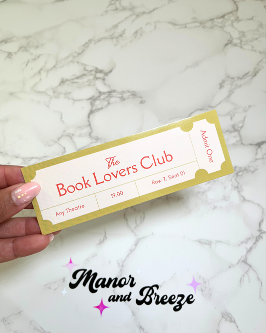 A pistachio green bookmark with 'The Book Lovers Club' text and a glossy finish, held by a hand against a marble background.