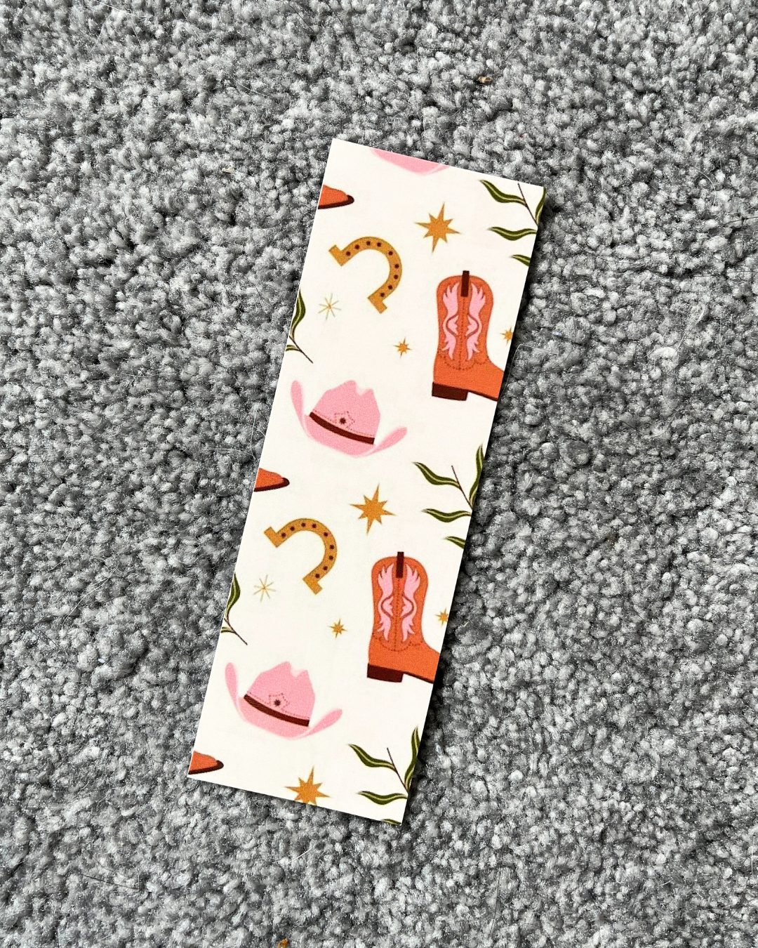 A bookmark with a cowboy boot design and various colorful illustrations on a glossy card background.